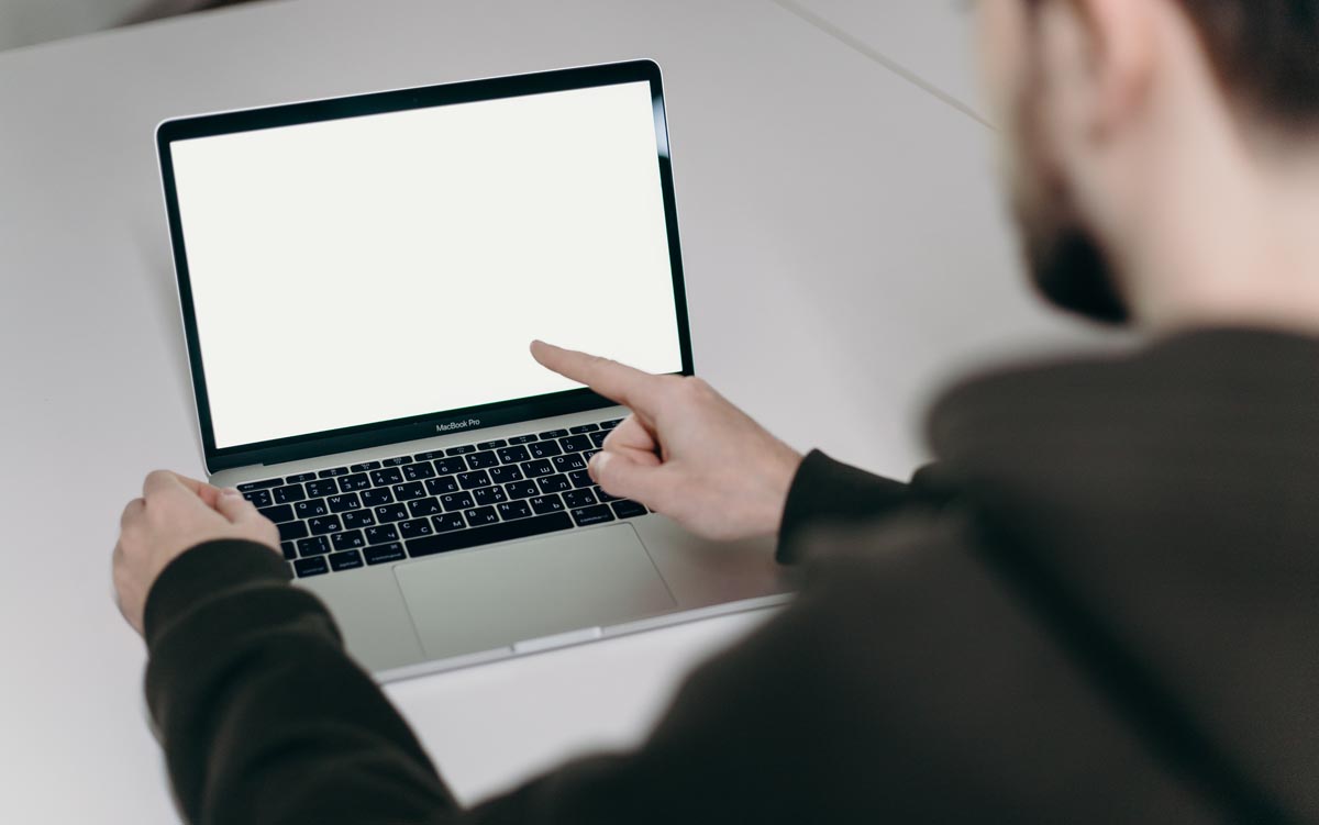 personne pointant vers un écran d'ordinateur portable vierge