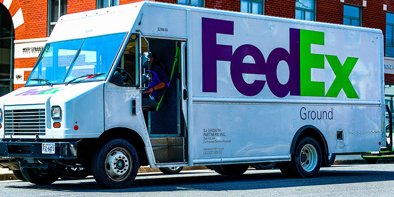 شاحنة بيضاء تابعة لشركة FedEx بداخلها رجل توصيل ، كانت متوقفة خارج مبنى مكاتب في واشنطن العاصمة في يوم مشمس.