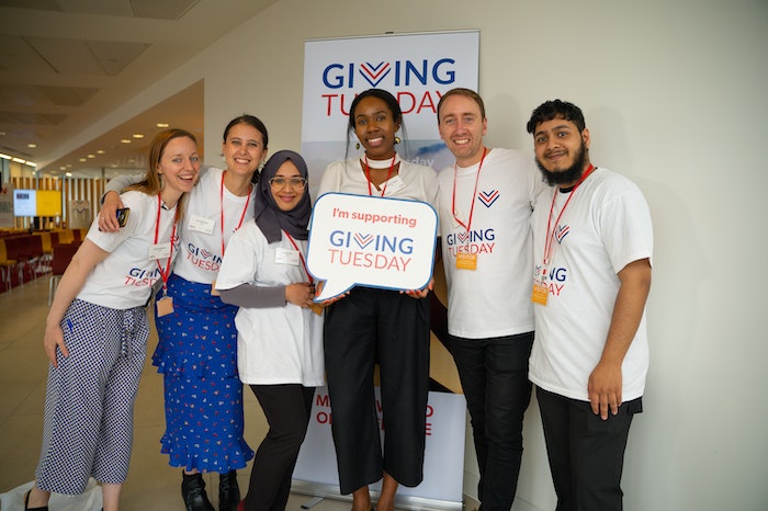 Eine Gruppe von Menschen hält ein Giving Tuesday-Schild in der Hand