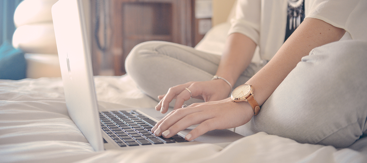 Persona seduta sul letto che digita sul computer