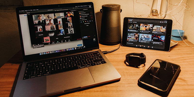 Un laptop, un tablet e un orologio su una scrivania marrone