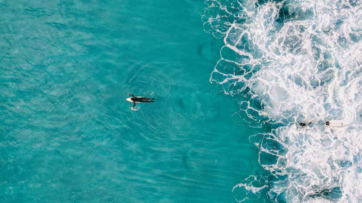 oceano blu turchese con surfista che nuota verso il mare.