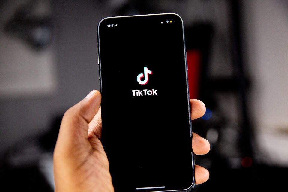 Hand Holding Phone Dengan Logo TikTok di Layar Hitam