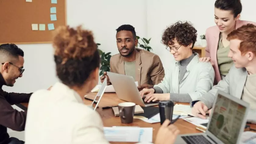 Un groupe de personnes assises autour d’une table avec des ordinateurs portables.