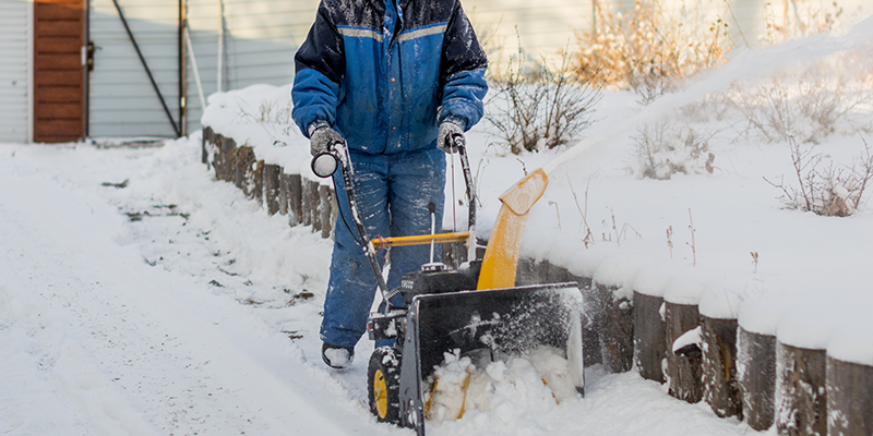 除雪機で雪かきをする男性